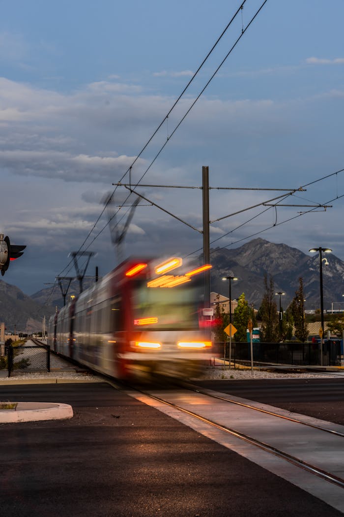 A dynamic shot of a train crossing a railroad with mountain backdrop during twilight.